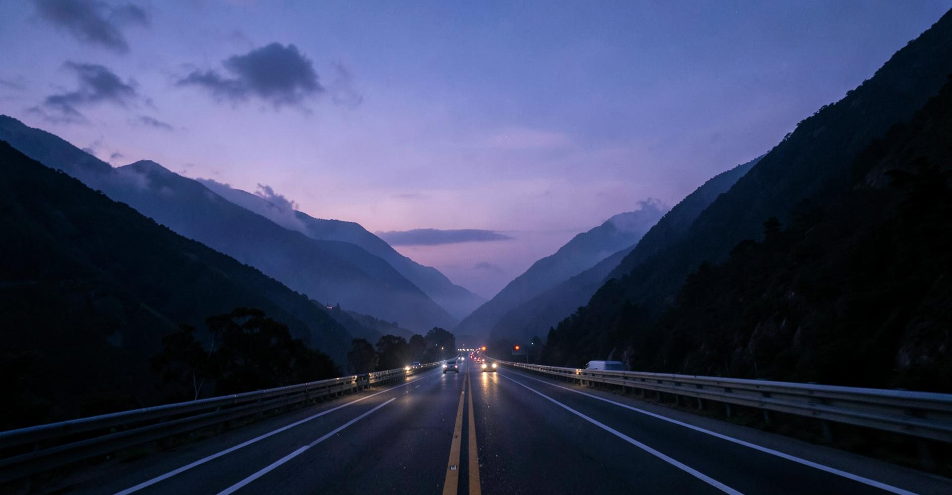 Highway curving through mountains at dusk